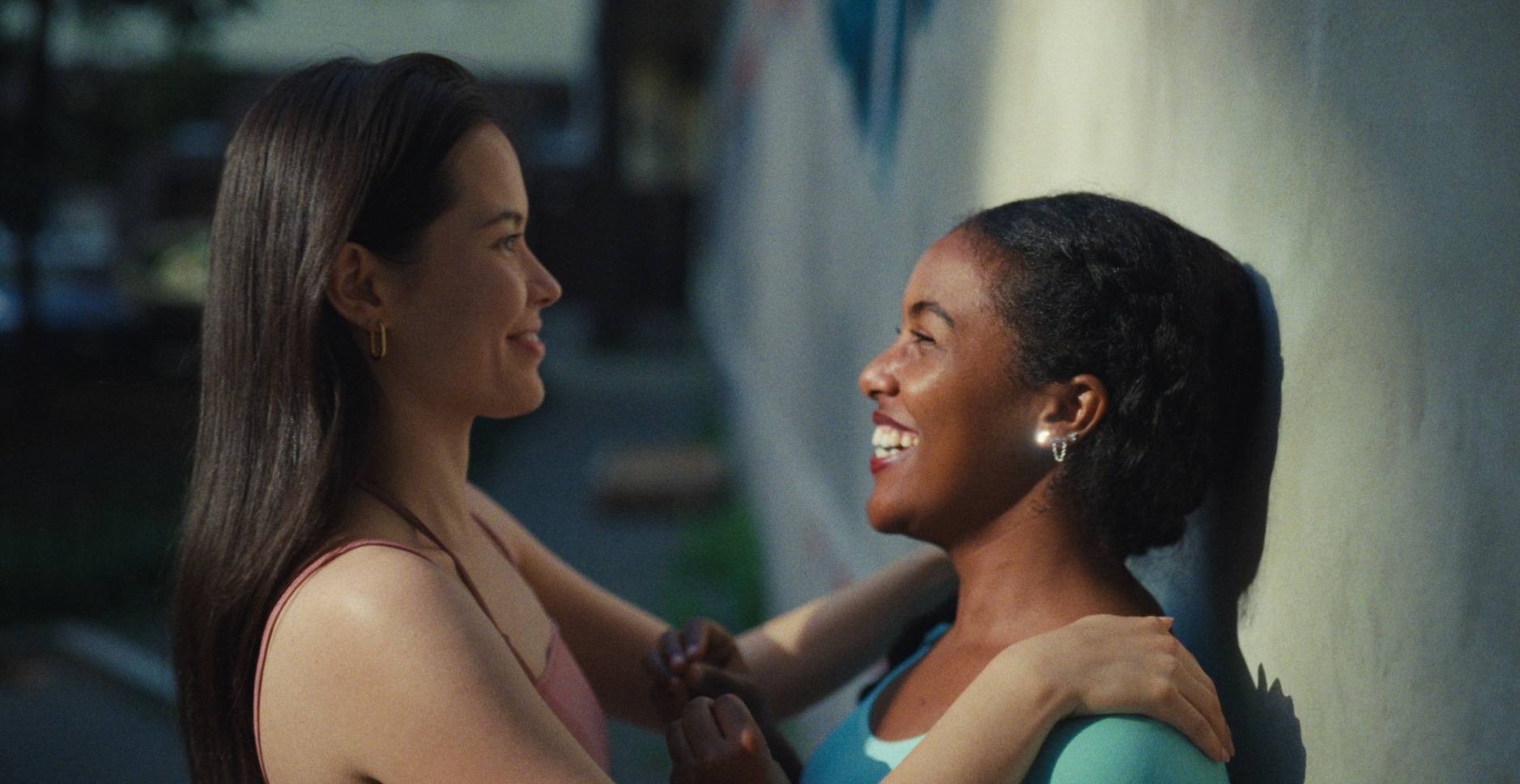 Two women smiling at each other in sunlight, illustrating a warm, toasted Filmbox look